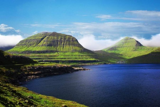 Dramatic green mountains and deep blue fjord waters showcase the stunning natural beauty of the Faroe Islands